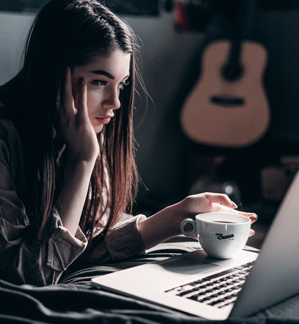 Jeune femme effectuant des recherches sur son ordinateur avec un café à la main